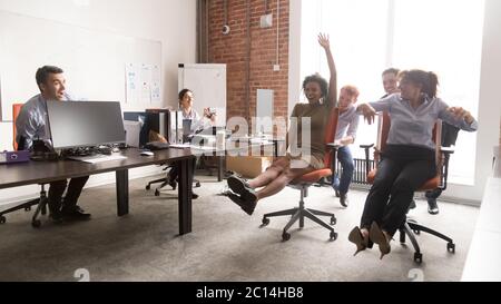 Joyeux collègues divers s'amusant ensemble, en prenant la chaise de bureau Banque D'Images