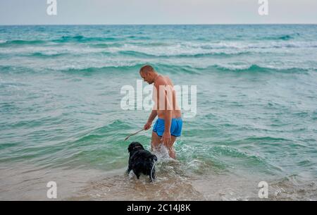 un homme avec un chien nageant dans la mer Banque D'Images