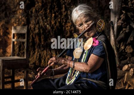 Ylacet Shen, une femme mature K'cho Chin avec des tatouages de visage, joue la flûte à nez traditionnelle, État de Chin, Myanmar Banque D'Images