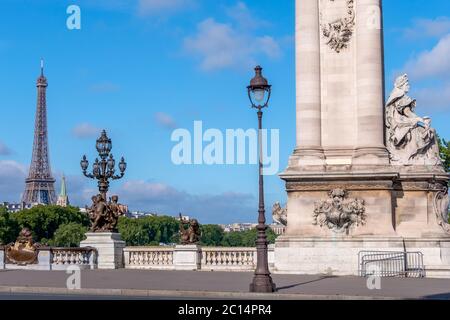 France. Journée ensoleillée d'été à Paris. Colonne et lanternes historiques sur le pont Alexandre III en face de la Seine. La Tour Eiffel au loin Banque D'Images