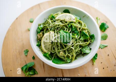 Spaghetti courgettes crues épinards végétaliens avec sauce sauce à l'avocat et citron dans un bol blanc. Sur fond en bois. Repas gastronomique italien. Vue de dessus Banque D'Images