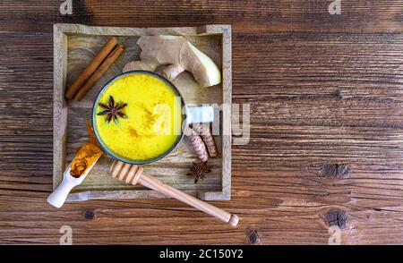 Plat de plateau avec du lait curcuma doré et des ingrédients : cannelle, miel, gingembre et espace de copie Banque D'Images