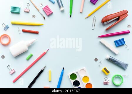 crayons, stylos sur fond bleu pastel. Bureau avec espace pour les copies au centre. Pose à plat. Banque D'Images