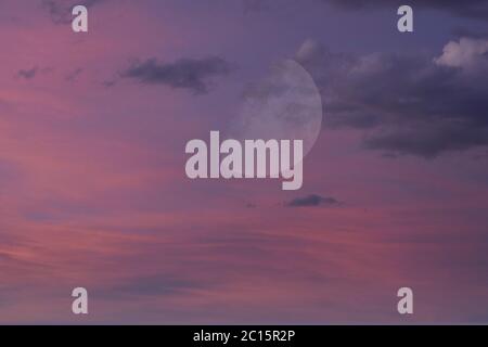 Lever du soleil tôt le matin au-dessus de Perceton à Irvine, en Écosse, avec un ciel rose et rouge flamboyant et une demi-lune cirant ou en déclin. Banque D'Images