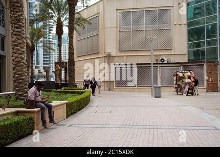 Dubaï / Émirats arabes Unis - 1 février 2020 : homme assis au téléphone dans la Marina de Dubaï Banque D'Images