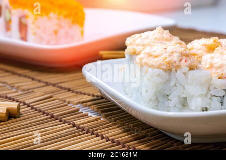 Sushi sur plaque blanche, bâtonnets de bambou sauce soja. Cuisine japonaise Banque D'Images