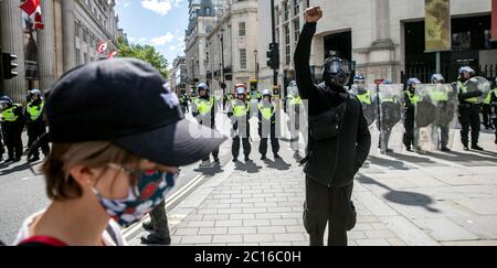 Pic shows: Black Lives Matter supporter devant la police anti-émeute a soulevé sa poing dans défi à Trafalgar Square samedi 13.6.20 photo par GA Banque D'Images