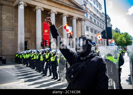 Pic shows: Black Lives Matter supporter devant la police anti-émeute a soulevé sa poing dans défi à Trafalgar Square samedi 13.6.20 photo par GA Banque D'Images