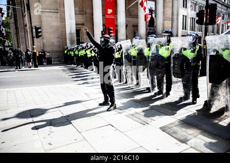 Pic shows: Black Lives Matter supporter devant la police anti-émeute a soulevé sa poing dans défi à Trafalgar Square samedi 13.6.20 photo par GA Banque D'Images