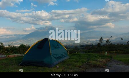 Tente de camping verte sur un terrain d'herbe avec le volcan Imbabura en arrière-plan par une journée nuageux Banque D'Images