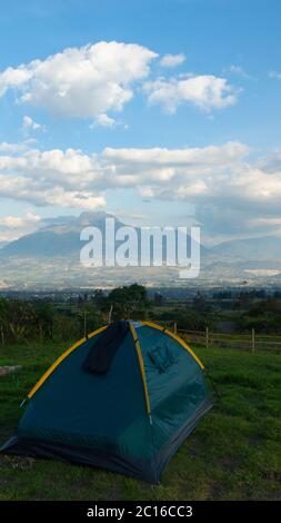 Tente de camping verte sur un terrain d'herbe avec le volcan Imbabura en arrière-plan par une journée nuageux Banque D'Images