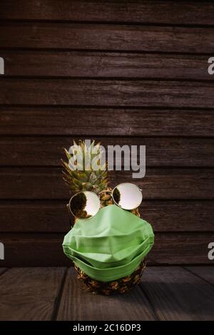 Ananas frais avec lunettes de soleil et masque facial sur fond de bois foncé. Photo de haute qualité Banque D'Images