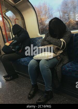 Deux passagers fatigués, une femme et un homme, se sont endormis à la tête sur le train souterrain de Londres, leurs visages ne sont pas visibles Banque D'Images