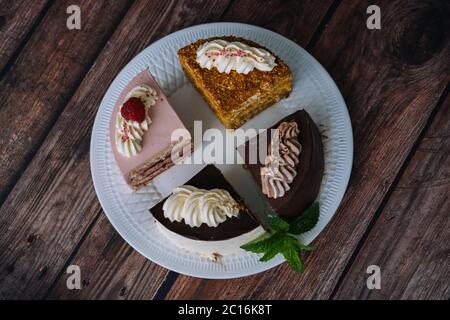 Collection de gâteaux divers sur fond de bois. Assortiment de morceaux de tranches avec crème. Assiette avec différents types de bonbons. Plusieurs tranches de délicieux desserts. Concept de menu de confiserie Banque D'Images