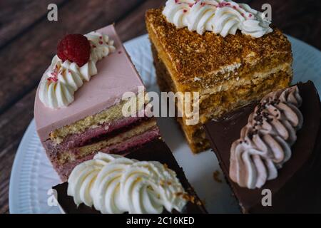 Collection de gâteaux divers sur fond de bois. Assortiment de morceaux de tranches avec crème. Assiette avec différents types de bonbons. Plusieurs tranches de délicieux desserts. Concept de menu de confiserie Banque D'Images