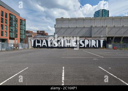 Texte « c'est l'esprit » peint sur le mur à côté du parking vide, avec des immeubles d'appartements et un bâtiment en béton Brutaliste Banque D'Images