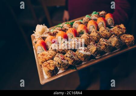 Ensemble de maintien pour serveur de gros plan Delicious Fresh Sushi ardoise plaque, poisson brut japonais chaud EBI sake Unagi . Philadelphia Flesh Rolls servis sur l'assiette i Banque D'Images