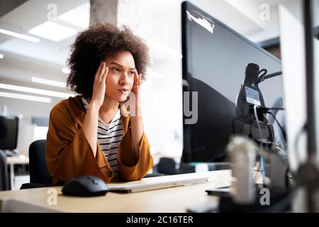 Surmené et frustré jeune femme en face de computer in office Banque D'Images