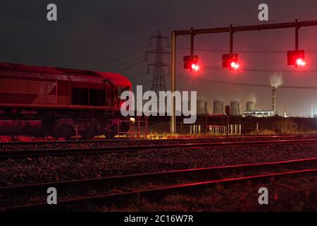 DB cargo classe 66 locomotive attendant à un signal rouge à Sudforth Lane , Knotingley avec la centrale électrique d'Eggborough et un pylône électrique en vue Banque D'Images