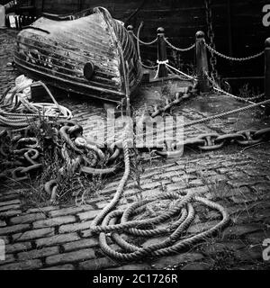 Image monochrome (noir et blanc) de petit bateau et de corde à l'arrêt sur Victoria Dock, Dundee, Écosse, Royaume-Uni. Banque D'Images