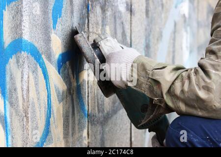 Enlèvement des graffitis sur un mur en béton d'un passage souterrain à l'aide d'une meuleuse d'angle. Banque D'Images