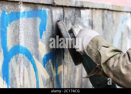 Enlèvement des graffitis sur un mur en béton d'un passage souterrain à l'aide d'une meuleuse d'angle. Banque D'Images