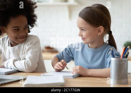 Les filles multiethniques s'assoient à table pour apprendre le sujet de l'école ensemble Banque D'Images