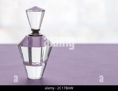 Vintage vide bouteille de parfum en verre cristal avec bouchon sur fond lilas Banque D'Images