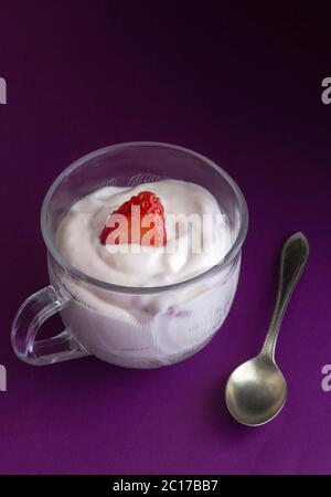 Yogourt aux fraises naturelles en petit verre tasse et cuillère à café sur fond violet close up Banque D'Images