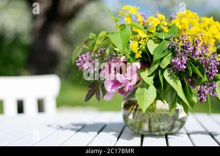 Bouquet de fleurs fraîchement cueillies du jardin dans un vase sur une table en bois blanc en plein air dans le jardin. Photo prise en Suède Banque D'Images