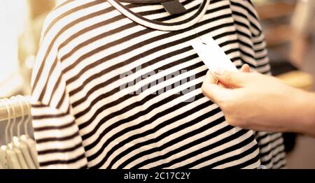 Gros plan la main de la femme en choisissant les vêtements qui pentent sur le rack dans le magasin. Les vêtements pendant les vêtements de shopping et choisir la tenue à acheter au tissu s Banque D'Images