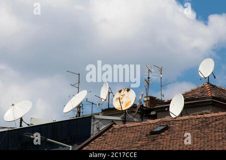 Antennes paraboliques et antennes tv montées sur le toit contre le ciel nuageux et ensoleillé Banque D'Images