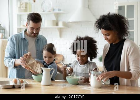 Une famille multiraciale avec des pâtisseries pour enfants rassemblées dans la cuisine Banque D'Images