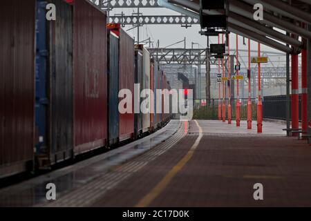 Train de conteneurs intermodal passant par la gare de Rugby sur la ligne principale de la côte ouest avec un signal ferroviaire rouge Banque D'Images