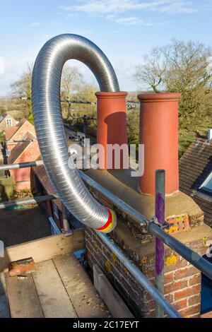 Installation d'un revêtement de cheminée en acier flexible dans une cheminée lors d'une installation de poêle à bois, Royaume-Uni Banque D'Images