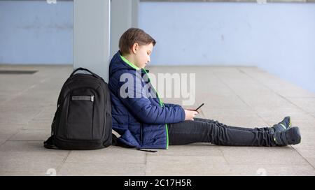 Concept de la vérité, jeune garçon restant loin de l'école et jouant à des jeux sur le mobile, martphone, absence de l'école Banque D'Images