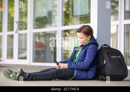 Truancy concept, jeune garçon restant loin de l'école et jouant à des jeux sur mobile ou smartphone, absence de l'école Banque D'Images