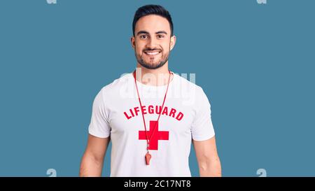 Jeune homme beau portant un uniforme de maître-nageur avec un sourire heureux et frais sur le visage. Personne chanceux. Banque D'Images