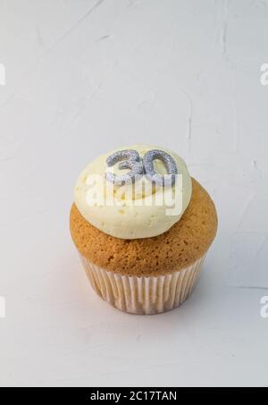 Gâteau de tasse à la vanille avec paillettes argentées numéro 30 sur un moule blanc crémeux Banque D'Images