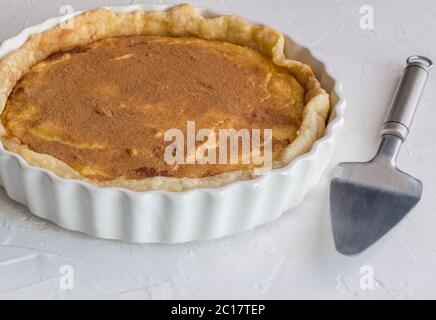 Tarte au lait arrosée d'épices à la cannelle sur fond texturé blanc rustique - tarte sucrée cru Banque D'Images