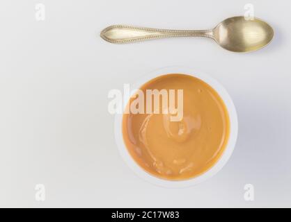 Fond de yaourt vue du dessus prise de yaourt au caramel dans une tasse en plastique avec une petite cuillère en argent Banque D'Images