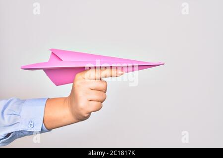 Main de la jeune femme caucasienne tenant un avion en papier sur fond blanc isolé Banque D'Images