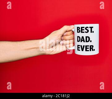 Belle main d'homme tenant une tasse de café avec le meilleur papa jamais message sur fond rouge isolé Banque D'Images