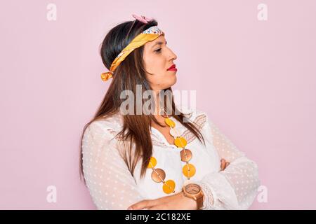 Jeune femme hippie hispanique portant le style boho de mode et des lunettes de soleil sur fond rose regardant sur le côté avec les bras croisés convaincu et de foi Banque D'Images