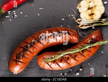 Saucisses grillées sur fond noir Banque D'Images