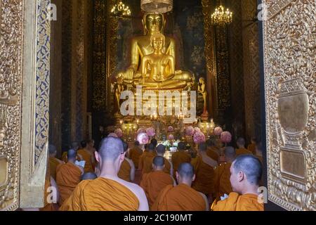 Les moines bouddhistes se sont rassemblés pour la prière dans le splendide hall de prière de Wat Boworniwet, Bangkok, Thaïlande, devant deux grandes statues de Bouddha doré Banque D'Images