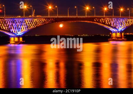 Les lumières nocturnes d'un grand pont de l'autre côté de la rivière se reflètent dans l'eau Banque D'Images