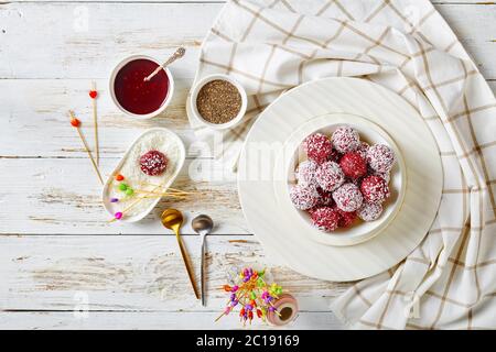 Beurre d'arachide et baies de forêt végétaliens : framboises, mûres, bleuets, boules de bisou avec graines de chia et noix de coco déshydratée sur une plaque blanche Banque D'Images