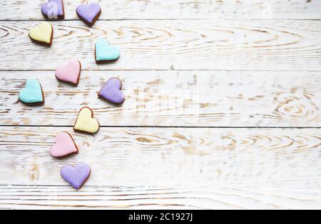 Biscuits coeur rose, violet, jaune et vert sur fond blanc en bois Banque D'Images