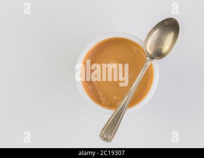 Fond de yaourt vue du dessus prise de yaourt au caramel dans une tasse en plastique avec une petite cuillère en argent Banque D'Images